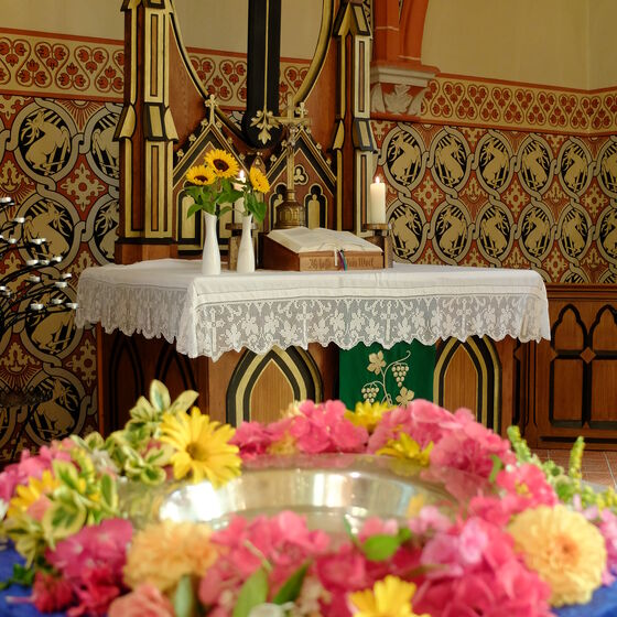 Taufbecken von St- Cäcilien in Sehlem mit Altar im Hintergrund
